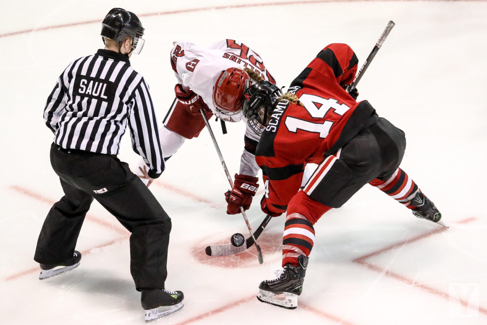Two players one in red and other in white playing ice hockey, with the referee present.